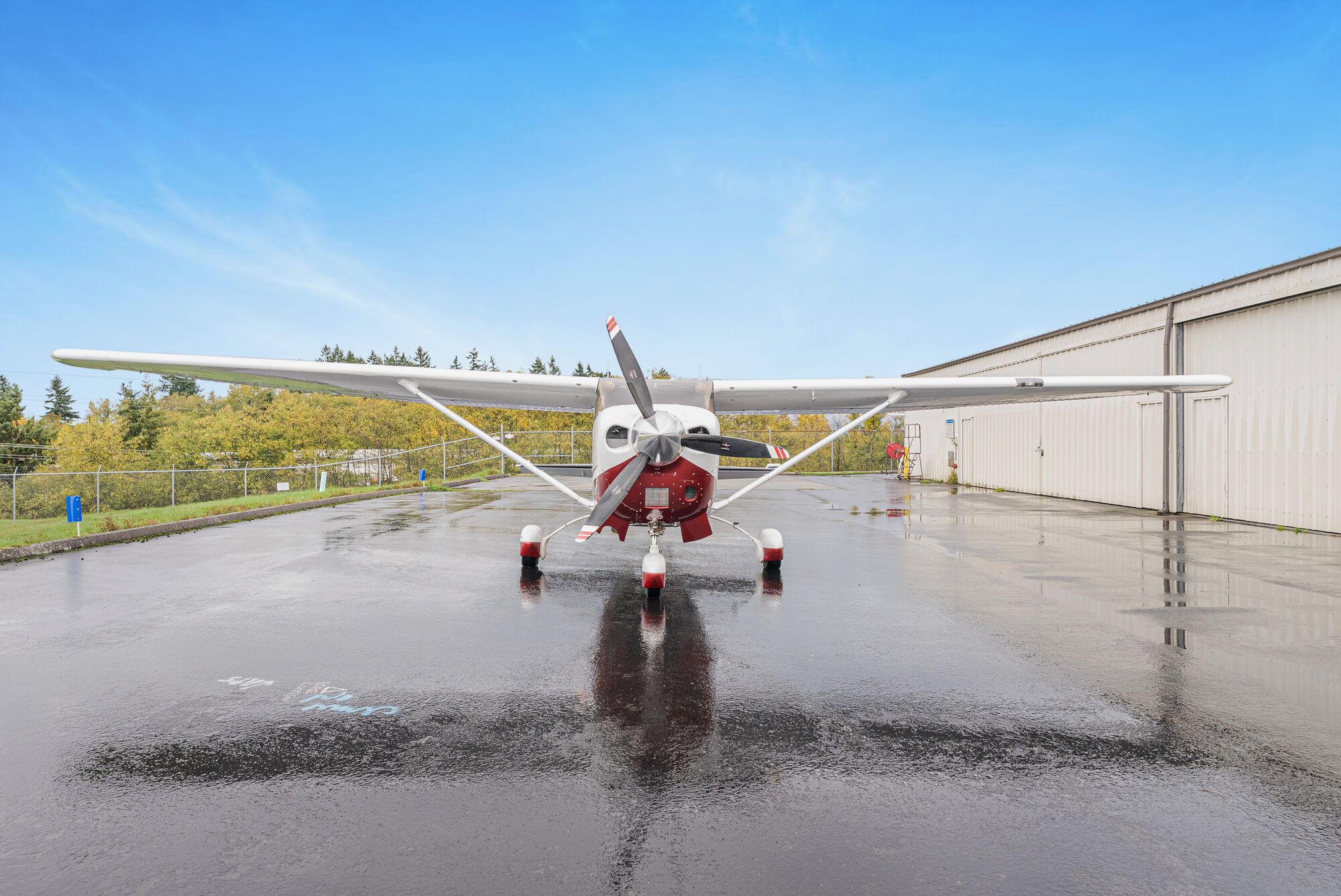 Cessna Turbo Stationair head on, on a wet ramp with its reflection, hangar to the right