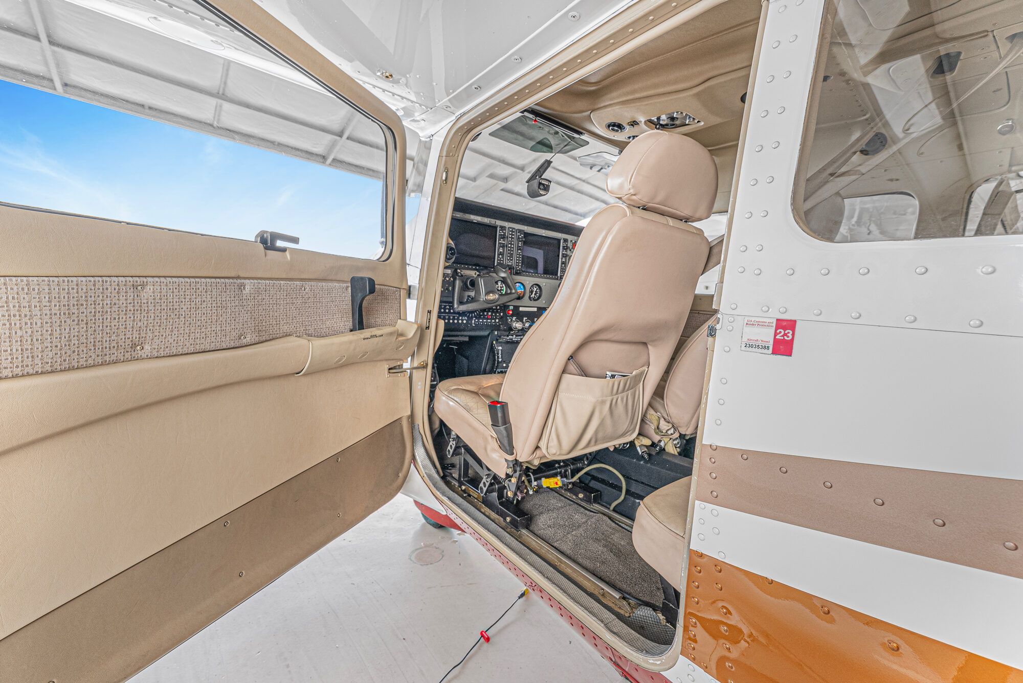 Cessna Turbo Stationair pilot door open, tan leather seat and the panel beyond