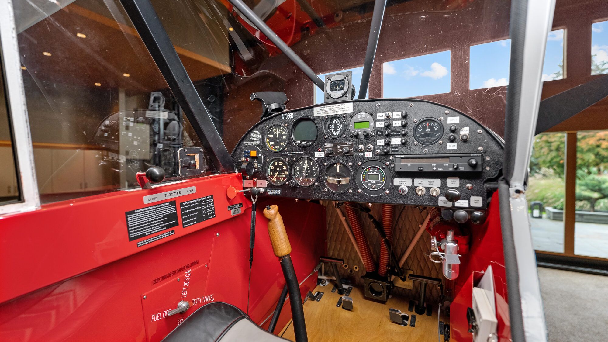 Super Cub instrument panel: round gauges, a red-painted cabin frame and the control stick