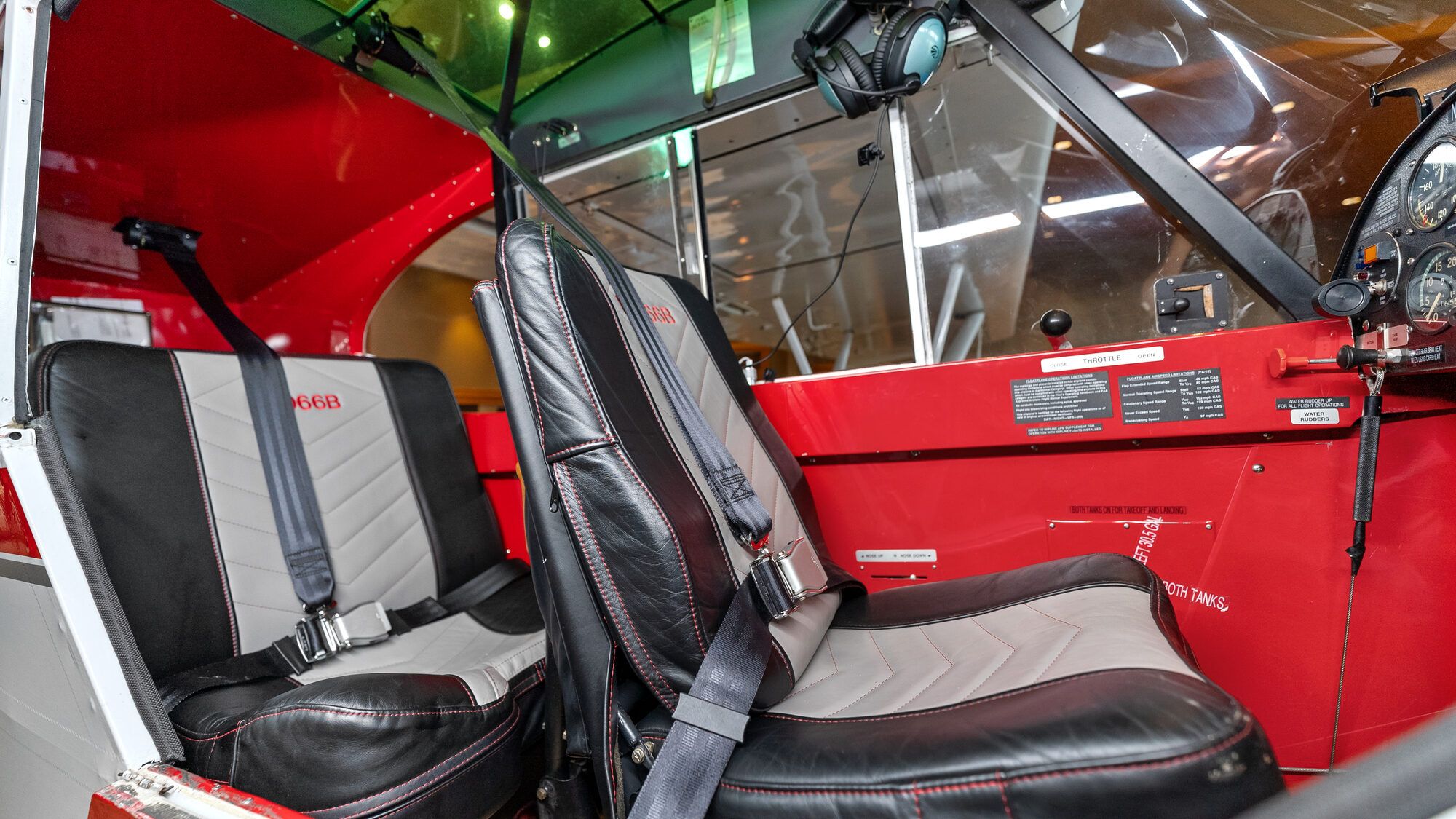 Super Cub tandem cabin with two black and grey leather seats and harnesses