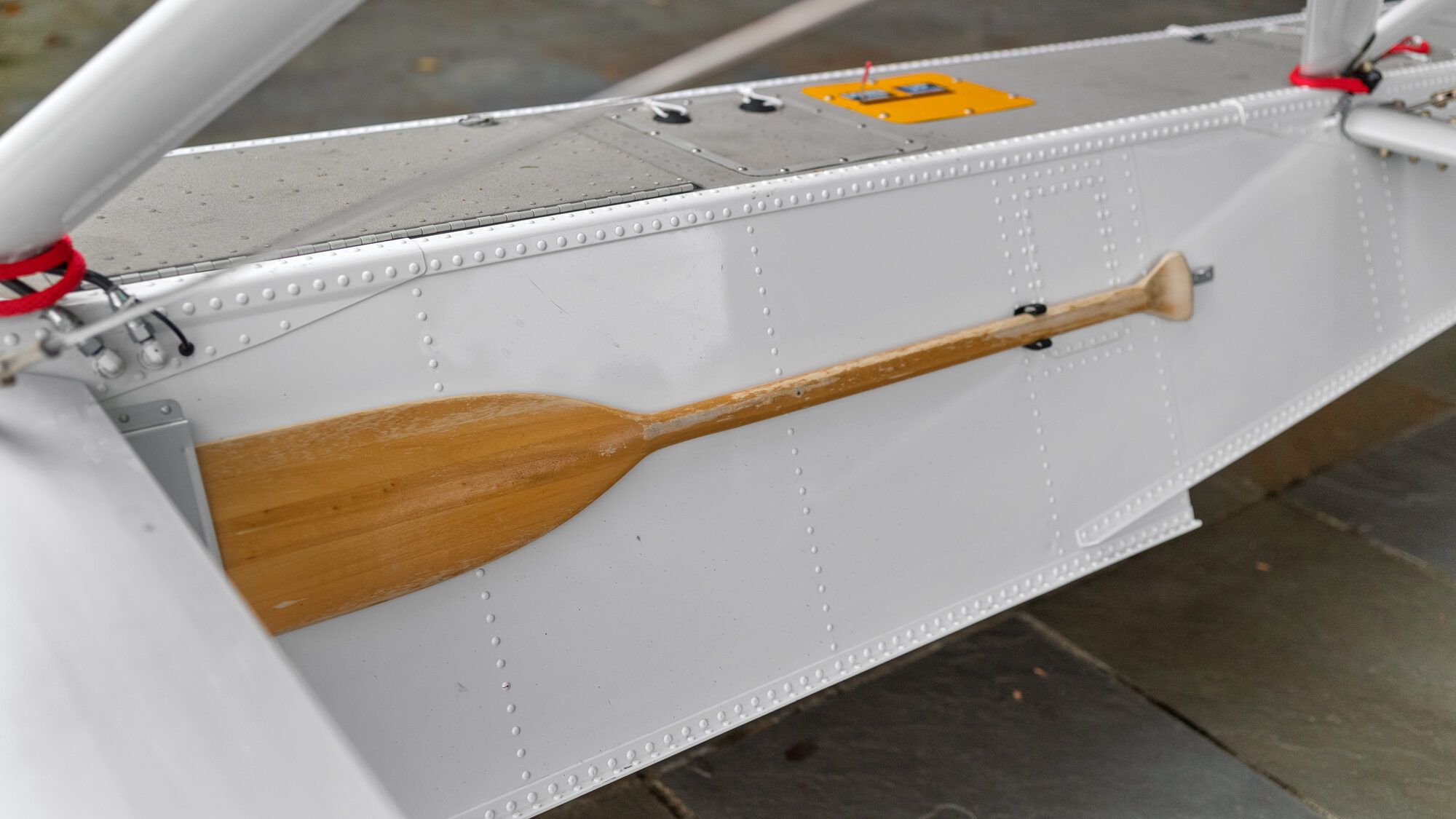 A wooden paddle stowed along the top of one float