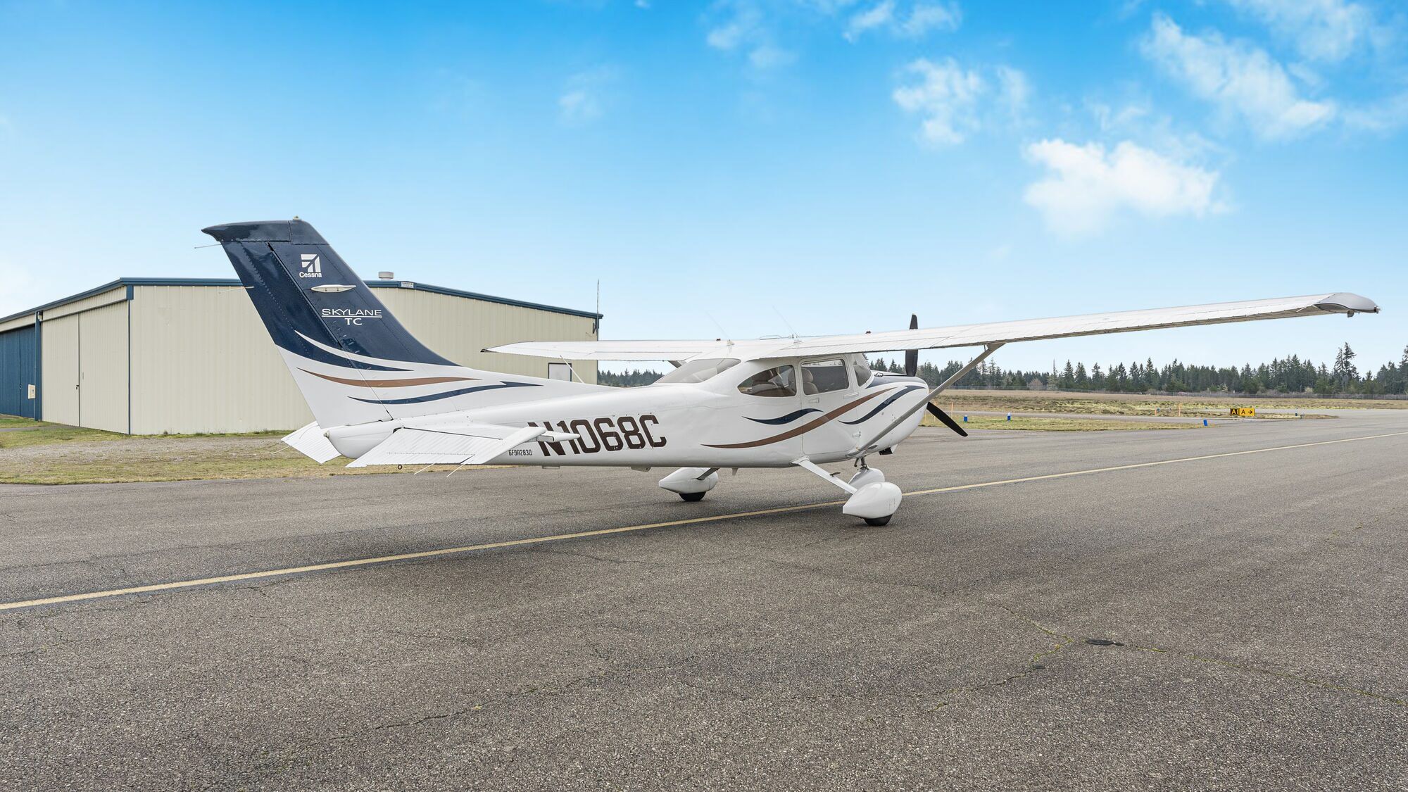 White Cessna Turbo Skylane parked on the ramp in front of a hangar