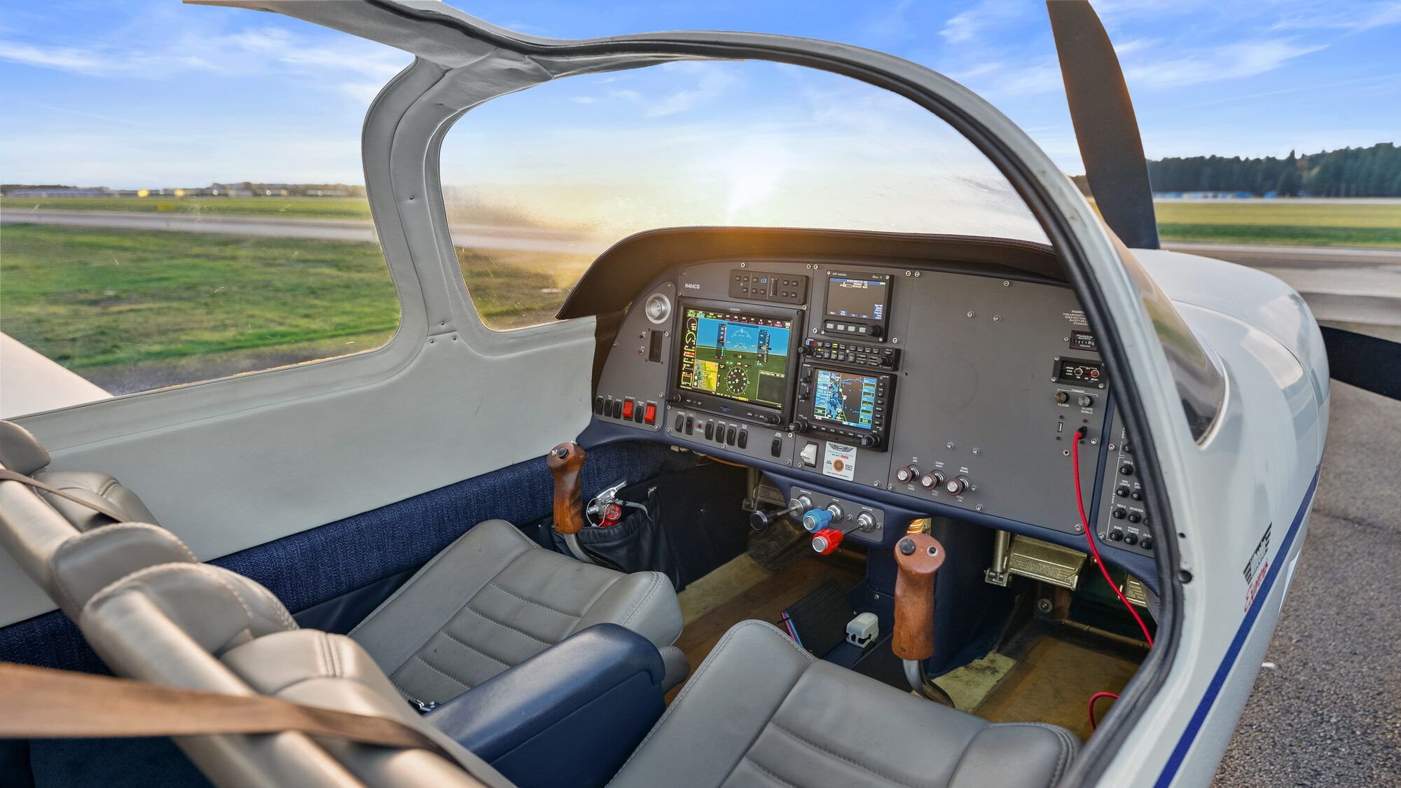 Wheeler Express cockpit through the open canopy at sunset, with a glass panel and grey leather seats