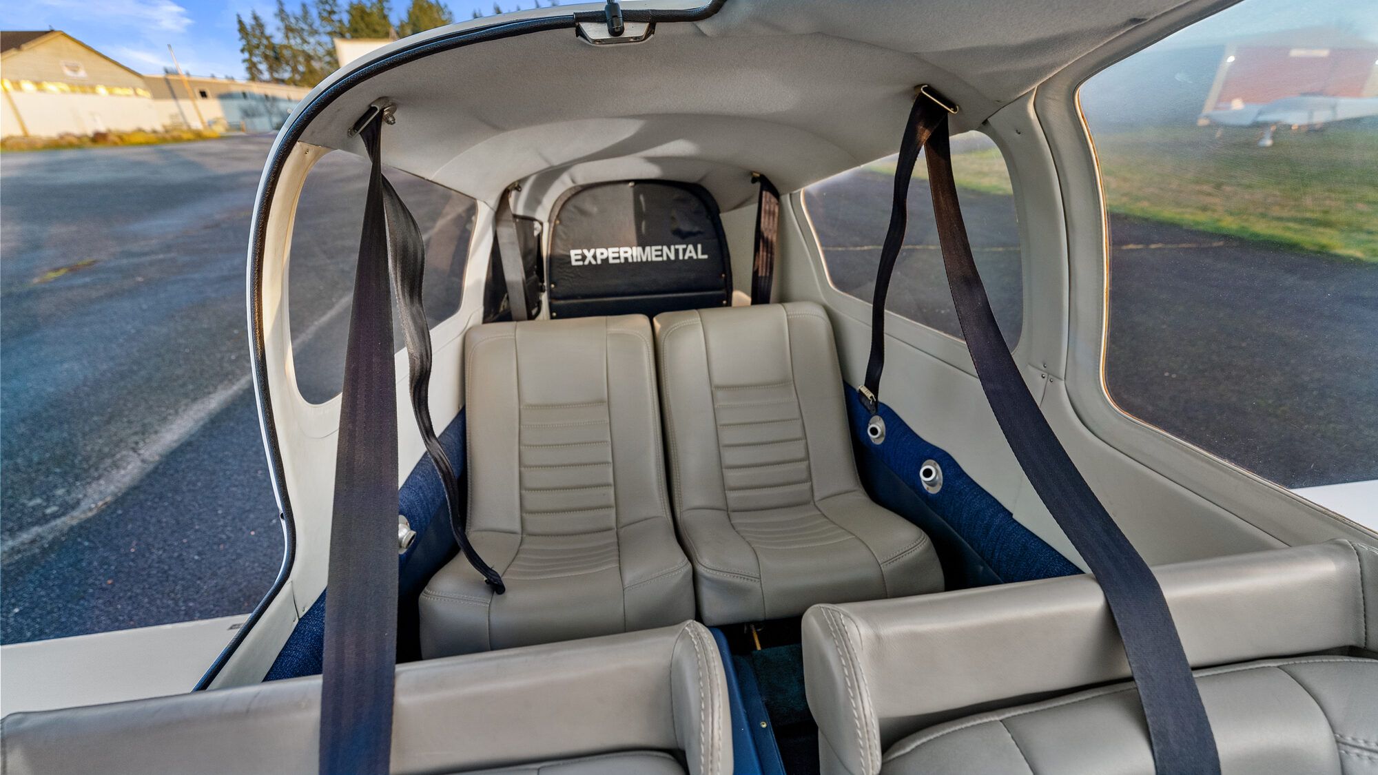 Wheeler Express cabin from behind: two grey leather seats, blue harnesses and the Experimental placard